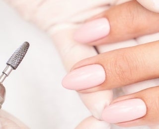 À esquerda, mão com luva segurando broca utilizada em alongamento de unhas. À direita, mão feminina com as unhas cuidadas.