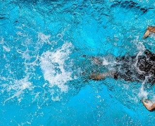 Homem praticando natação em piscina, uma forma de obter os benefícios da atividade física.  
